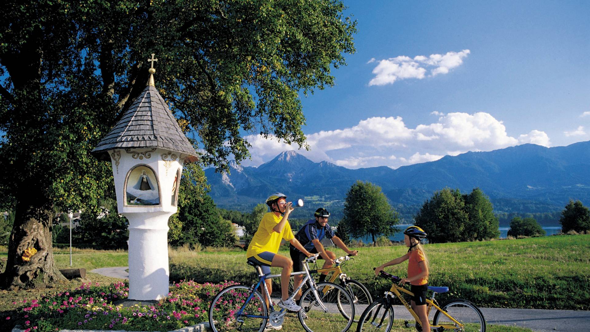 Familie beim Radfahren vor einem Bildstock