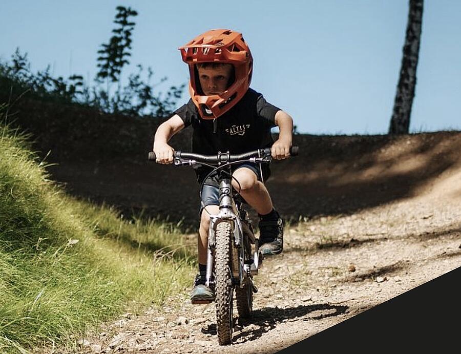 Kleiner Junge mit Schutzausrüstung am Pump Track Drobollach
